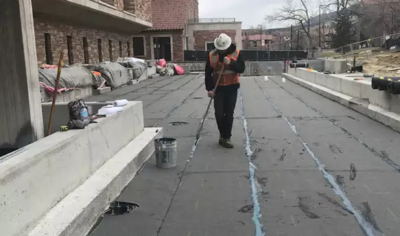 Construction worker laying Hot Fluid-Applied Rubberized Asphalt