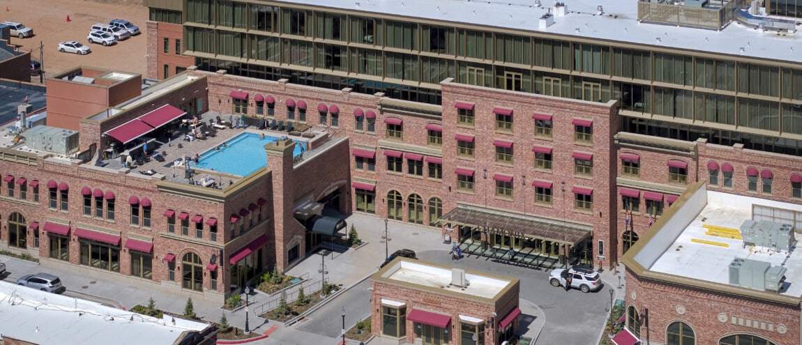 Aerial view of hotel with rooftop pool and red awnings