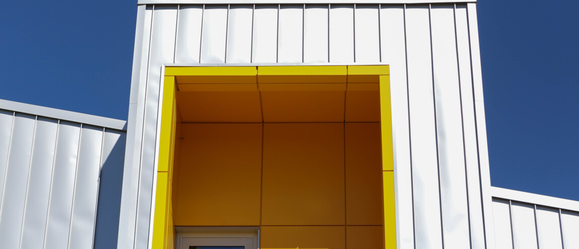 Modern building with yellow recessed window against blue sky