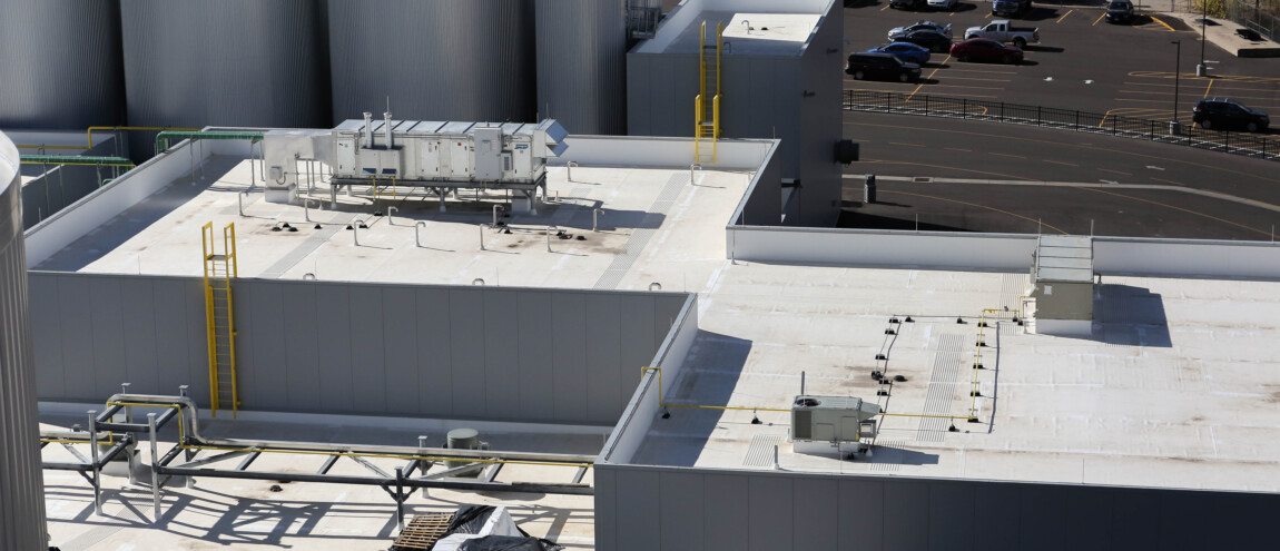 Industrial rooftop with equipment and parking lot in background