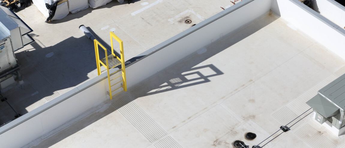 A rooftop with a yellow ladder and materials stacked.