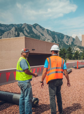 Construction workers walking on a commercial roof in colorado