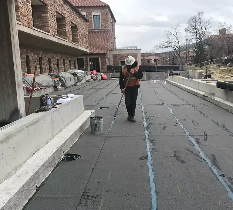 Construction worker laying Hot Fluid-Applied Rubberized Asphalt