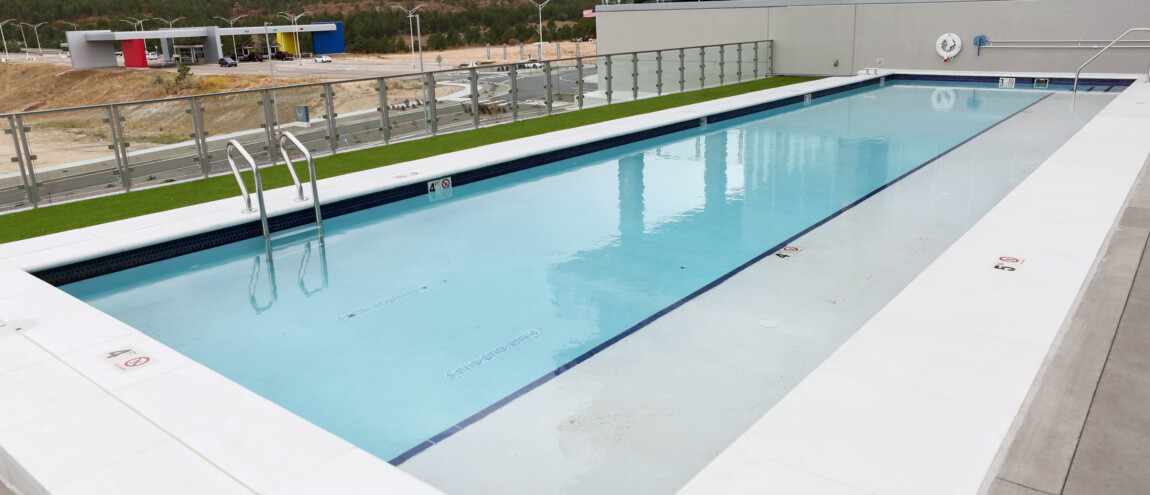Rooftop swimming pool with glass railing and mountain view