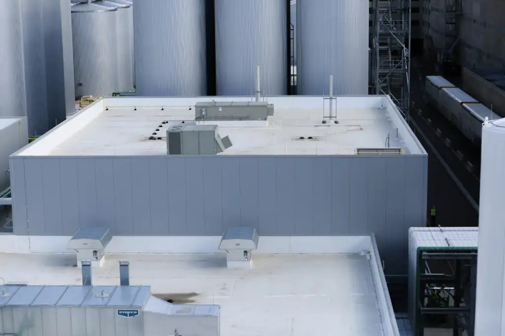 Industrial rooftop with equipment and large silo tanks.