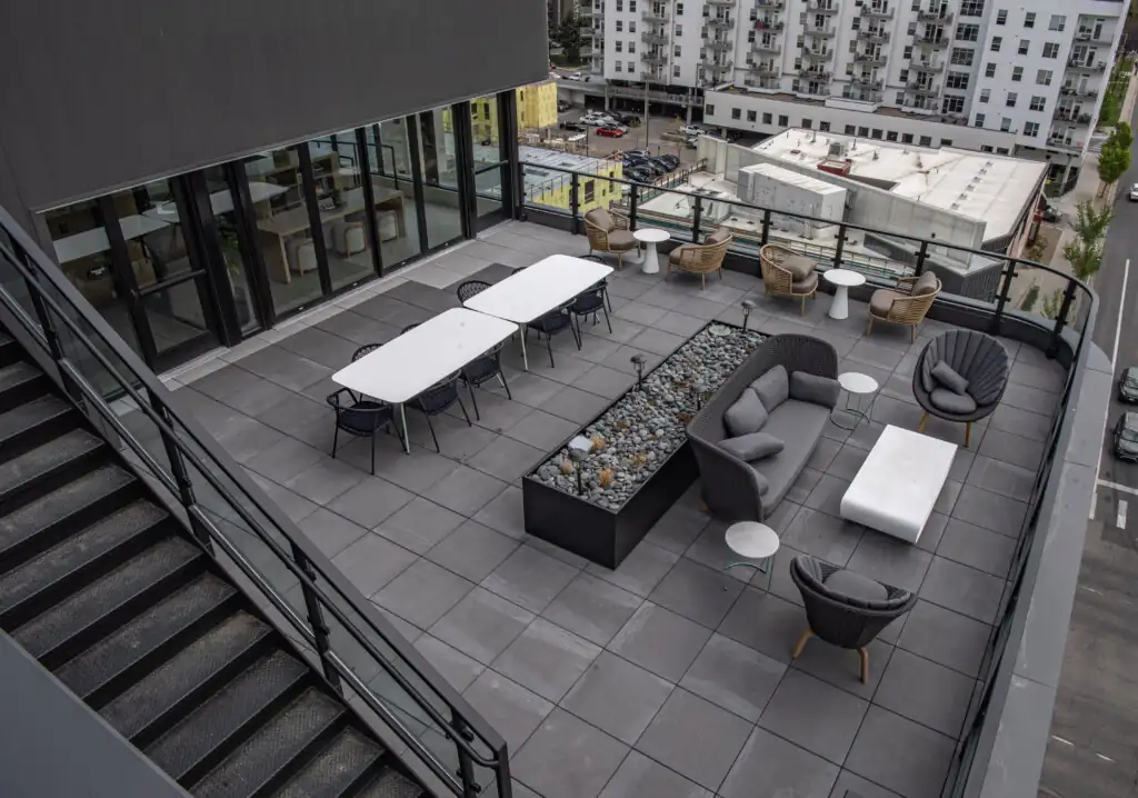 Outdoor rooftop terrace with seating and tables, city view