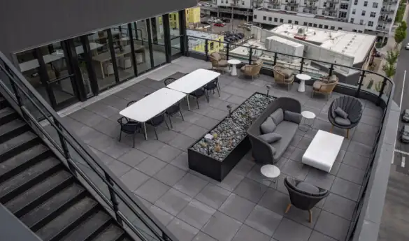 Outdoor rooftop terrace with seating and tables, city view